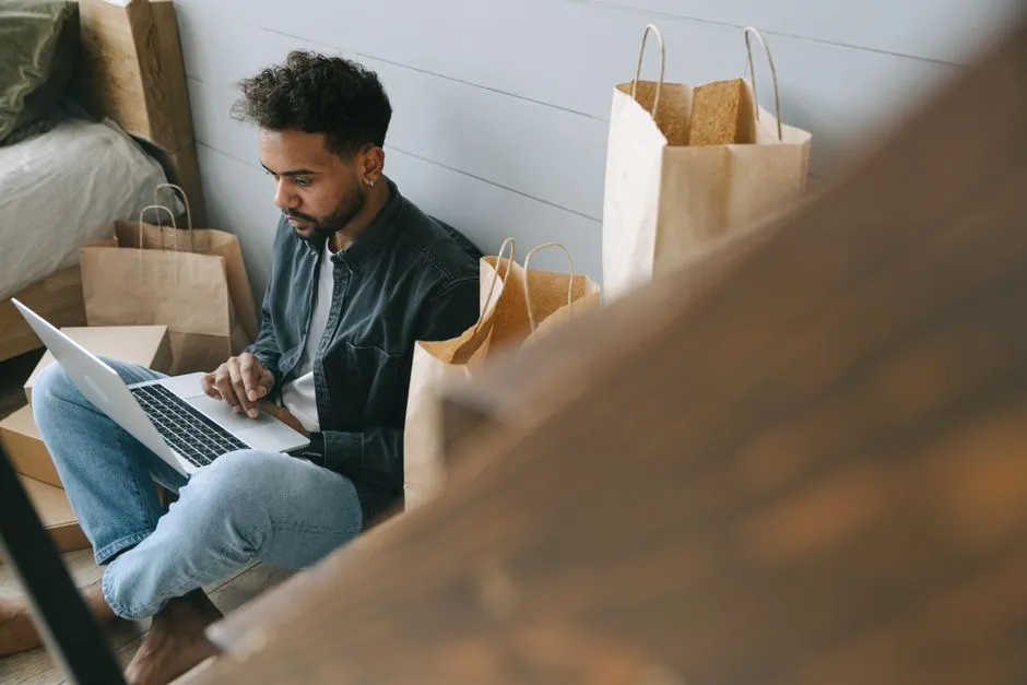 Person sitting with a laptop and shopping bags, an illustrative stock photo representing online deal hunting